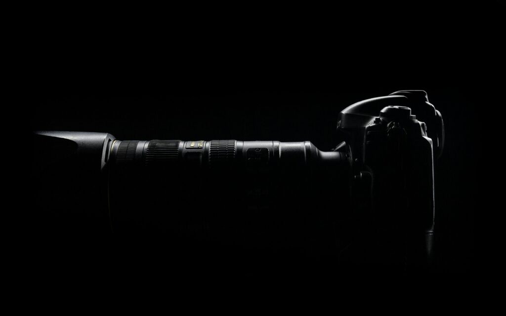 Artistic side profile of a DSLR camera with lens in dark setting.